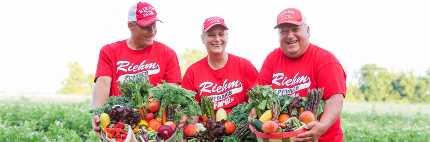 Riehm family farmers holding produce baskets